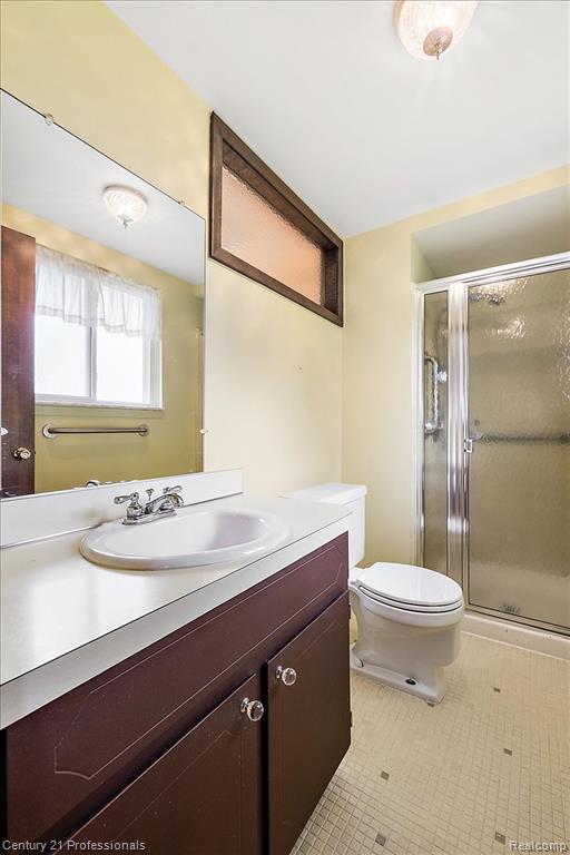Full bath with vanity, a shower stall, and light tile patterned flooring