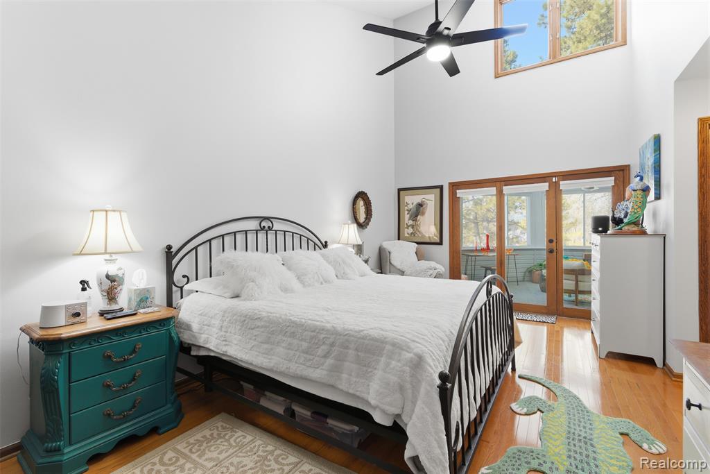 Bedroom with french doors, a high ceiling, light wood finished floors, access to exterior, and a ceiling fan