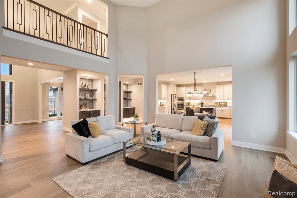 Living area with light wood-style flooring, a high ceiling, recessed lighting, and a chandelier