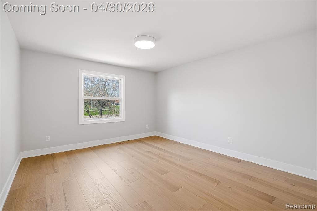 Empty room featuring baseboards and light wood-type flooring