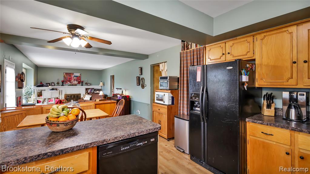 Kitchen featuring black appliances, dark countertops, a ceiling fan, light wood-type flooring, and beamed ceiling