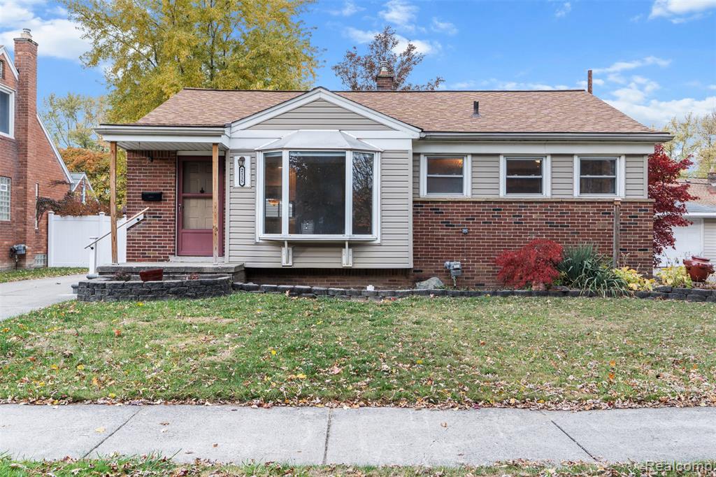 Bungalow featuring a front yard, brick siding, and a chimney