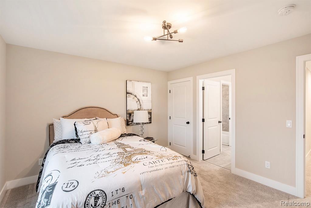 Bedroom featuring light colored carpet, a chandelier, and ensuite bathroom