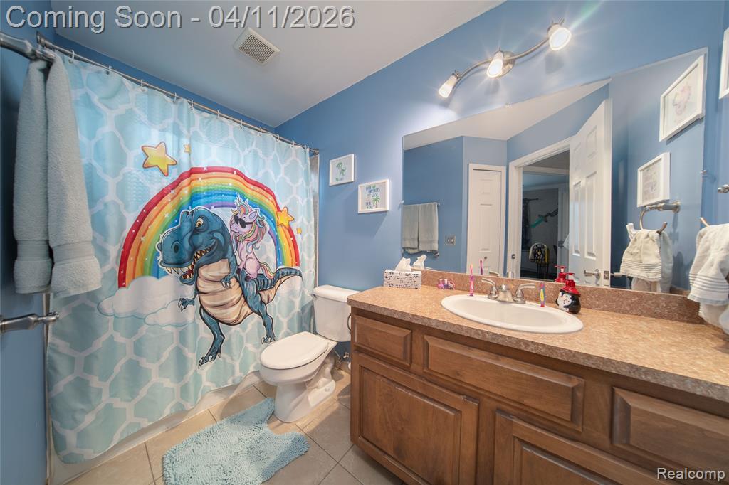 Bathroom featuring vanity, light tile patterned flooring, and curtained shower