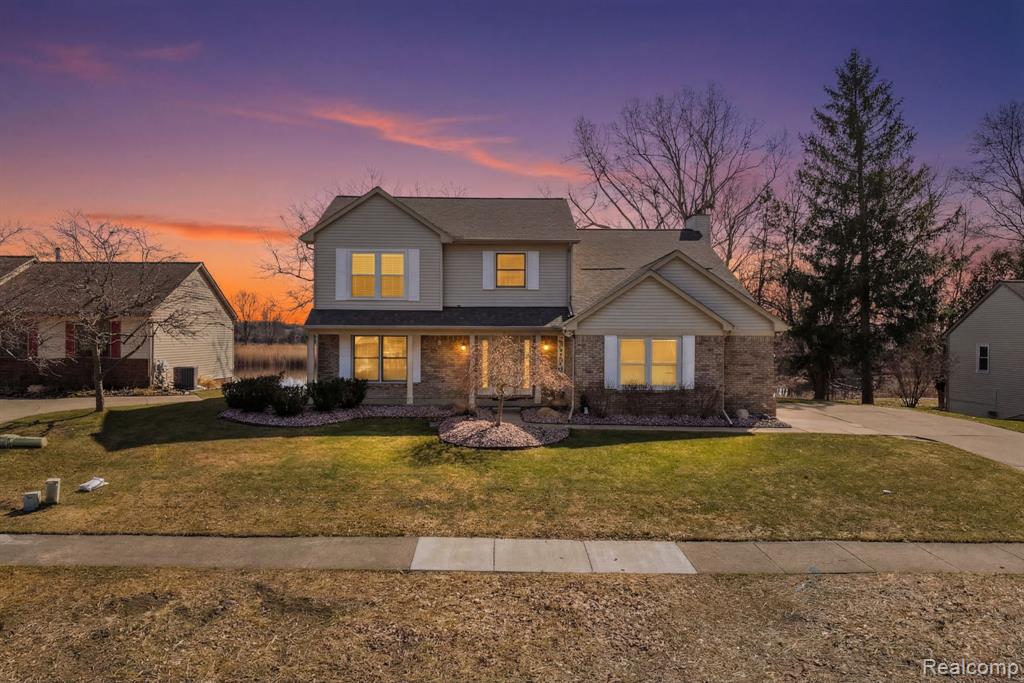 Traditional-style home with a front yard, a porch, and brick siding