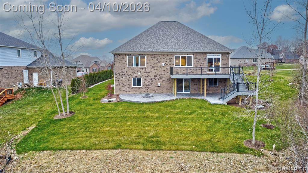Back of property featuring a patio, brick siding, a deck, and a residential view