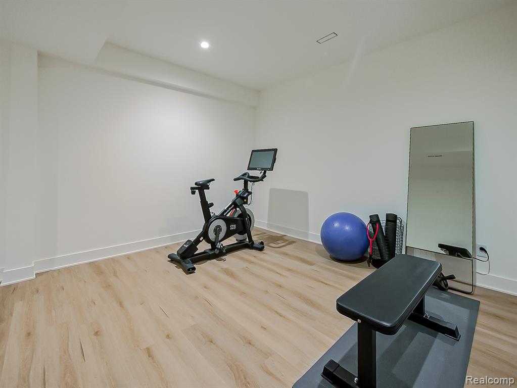 Exercise area with light wood-type flooring and recessed lighting