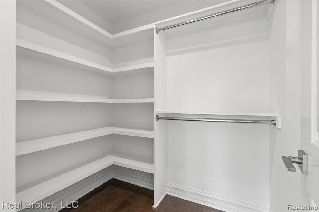 Walk in closet with dark wood-style floors
