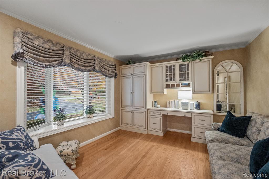 Home office featuring crown molding, light wood finished floors, and built in desk