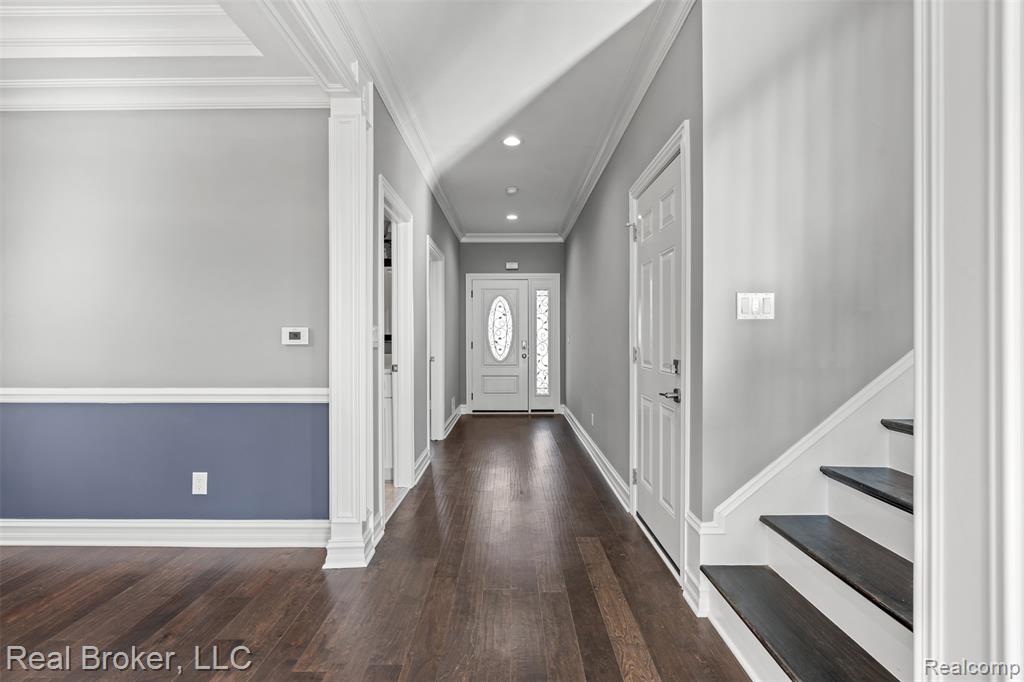 Foyer entrance with dark wood finished floors, recessed lighting, stairway, crown molding, and decorative columns