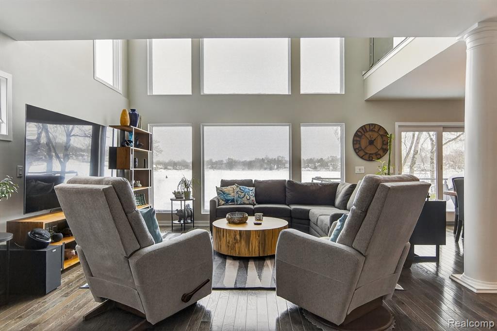 Living area featuring a high ceiling, dark wood-style floors, and ornate columns