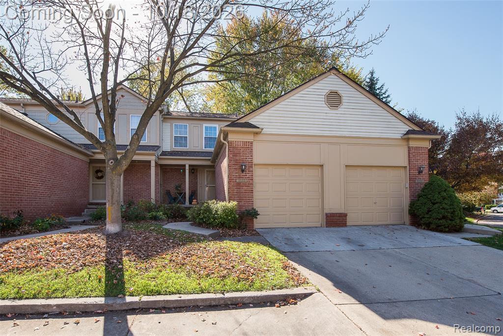 Two-story brick and siding exterior featuring a dual-bay garage, concrete driveway, and covered entryway
