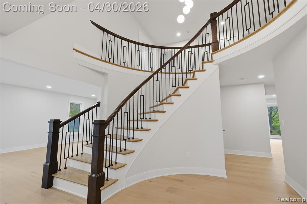 Staircase featuring wood finished floors, a high ceiling, and recessed lighting