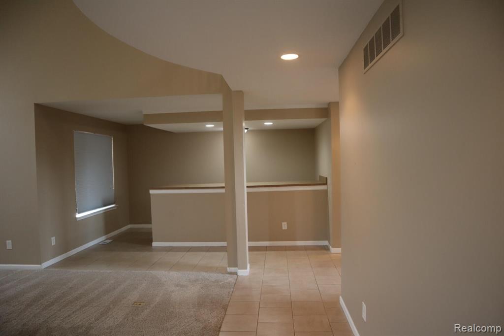 Unfurnished living room with a fireplace with flush hearth, carpet floors, and plenty of natural light