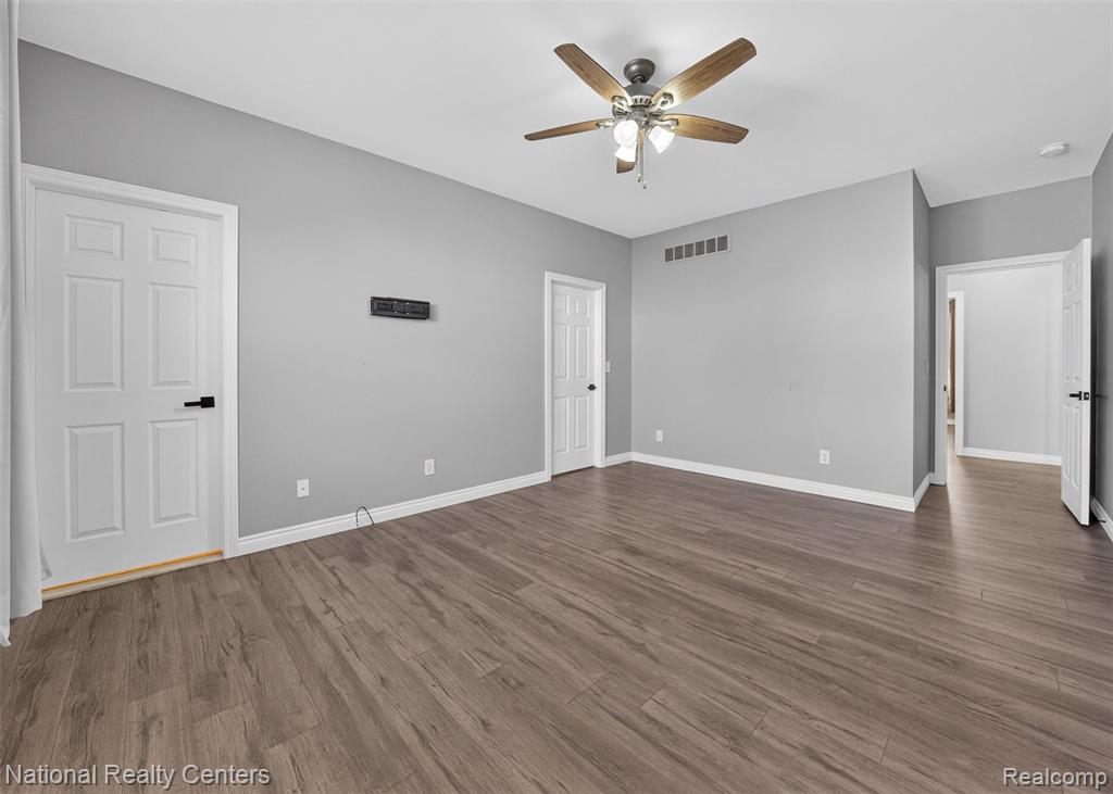 Unfurnished bedroom featuring a ceiling fan and dark wood-style floors
