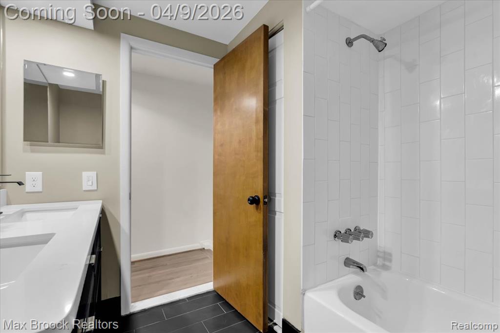 Bathroom with double vanity, shower / bathtub combination, and dark tile patterned floors
