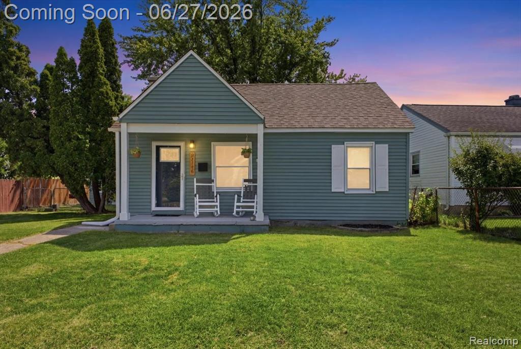 Charming single-story residence featuring a covered front porch, teal horizontal siding, and a brown asphalt shingle roof