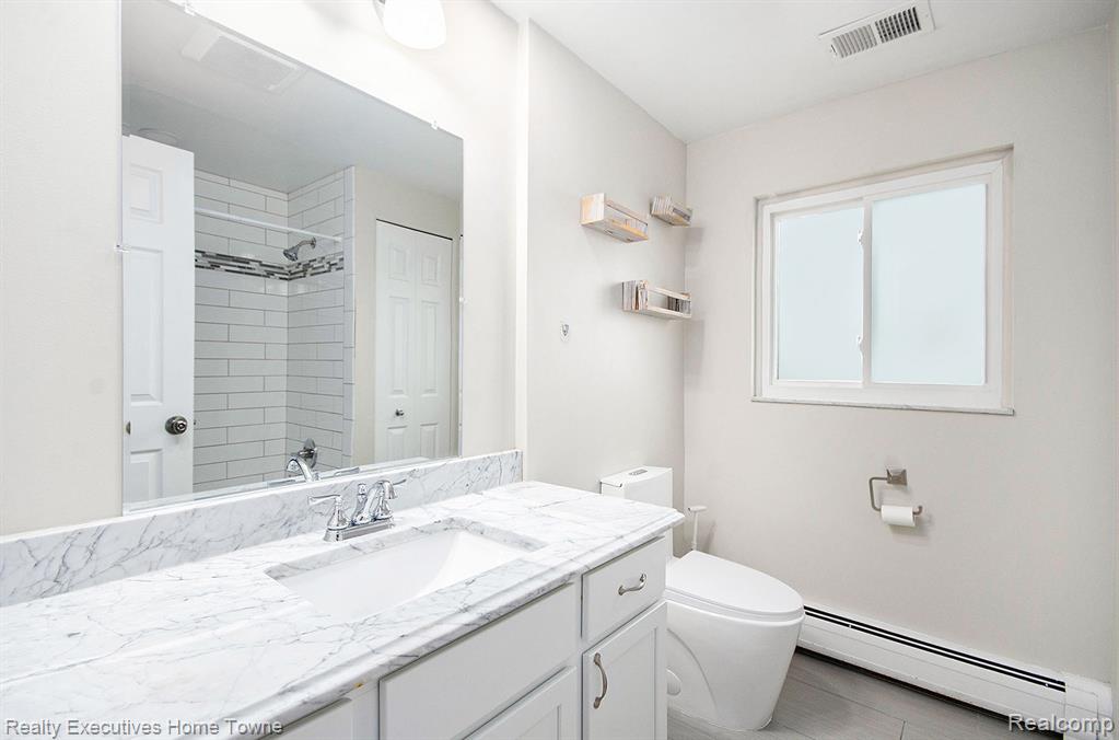 Bathroom with baseboard heating, vanity, and a shower