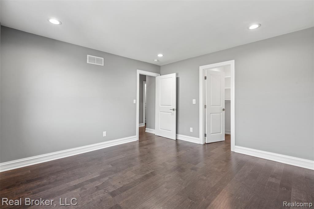 Unfurnished bedroom with a spacious closet, recessed lighting, and dark wood finished floors