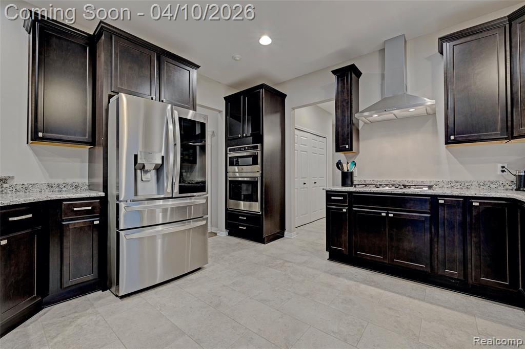 Kitchen with stainless steel appliances, light stone countertops, recessed lighting, and dark wood finish cabinets