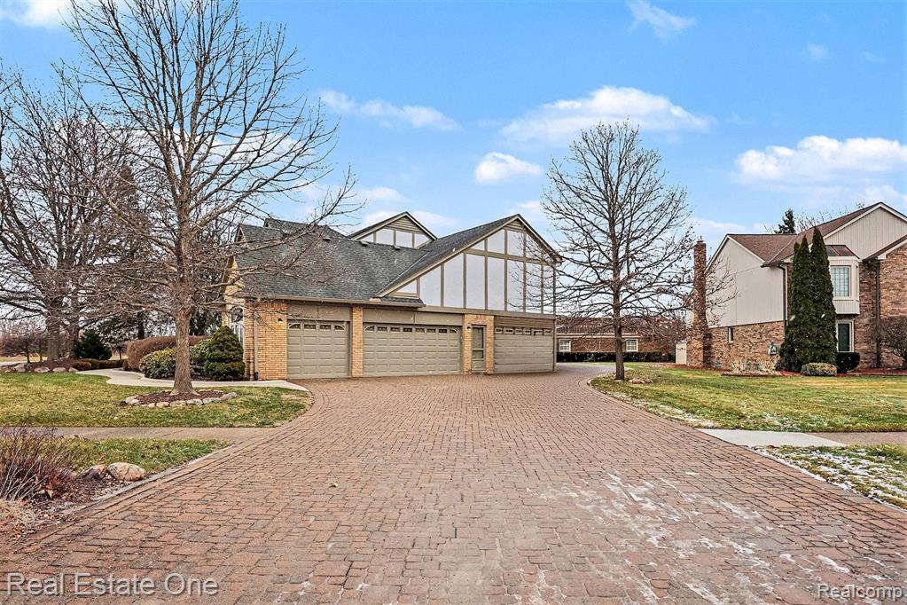 View of front of property featuring decorative driveway, a front yard, a garage, and brick siding
