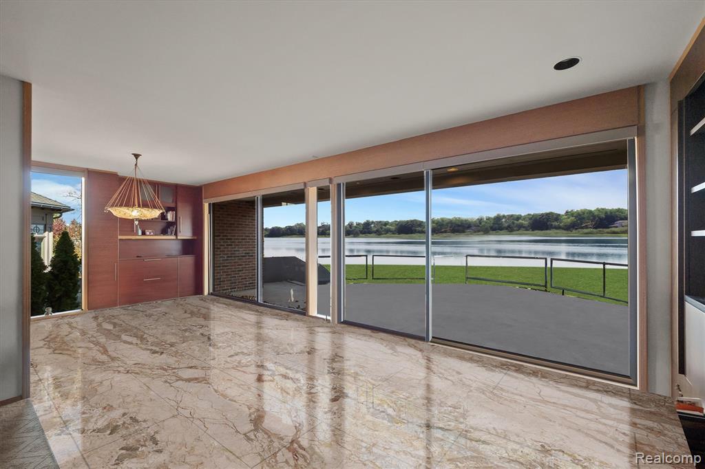 Empty room with light marble finish flooring, a water view, and healthy amount of natural light