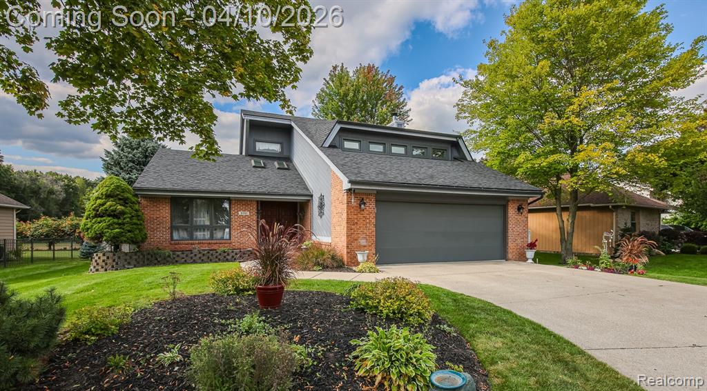 Mid-century modern home featuring brick siding, roof with shingles, driveway, and an attached garage