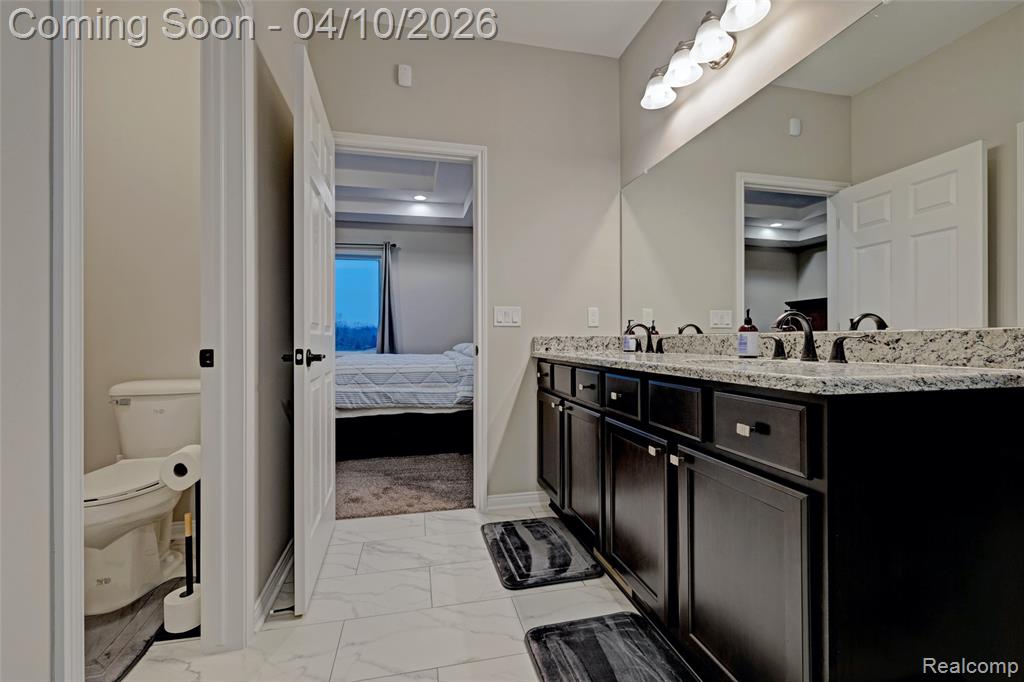 Bathroom with light marble finish flooring, connected bathroom, and double vanity