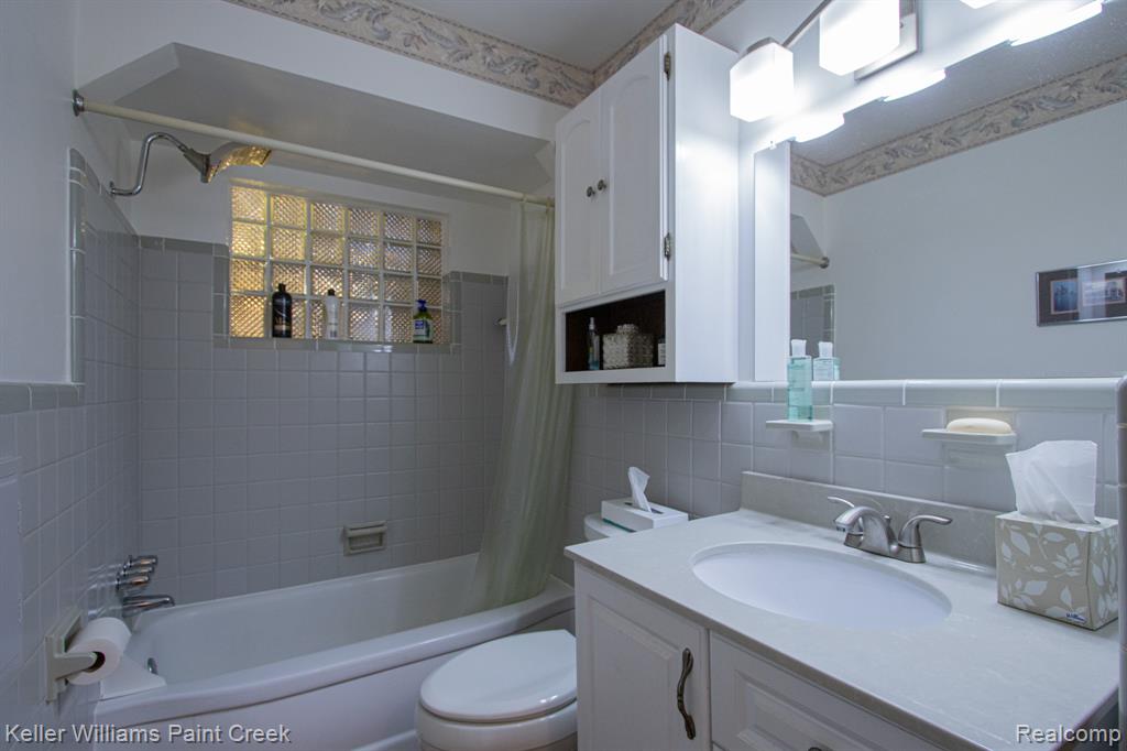 Bathroom with tile walls, vanity, and shower / bath combination with curtain