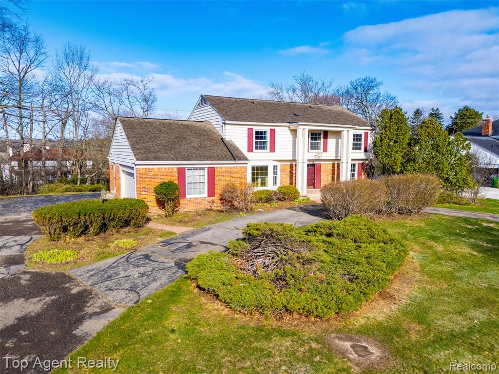 View of front of home featuring a front yard, brick siding, a shingled roof, and asphalt driveway
