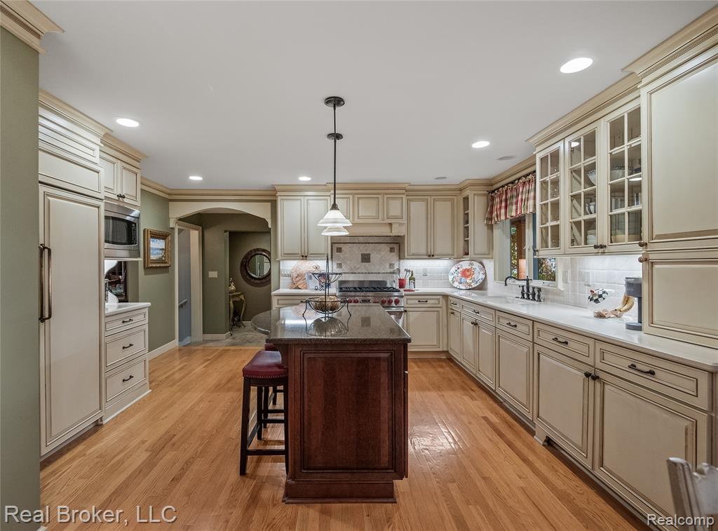 Kitchen featuring cream cabinets, arched walkways, a breakfast bar, dark stone countertops, and pendant lighting