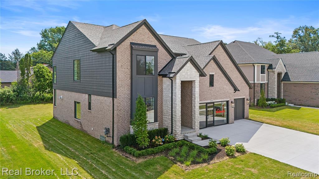 View of front of house with brick siding, driveway, a front yard, and a garage