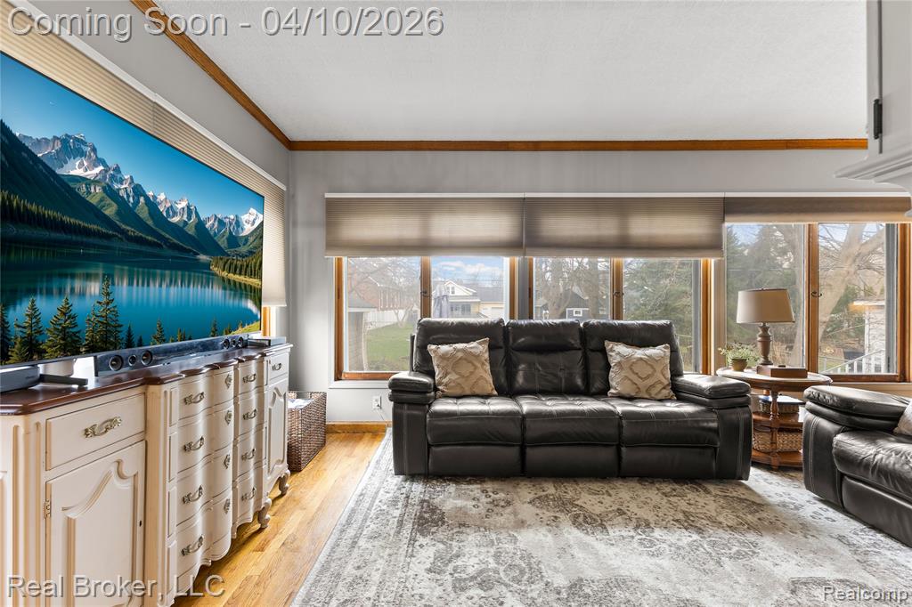Living room with light wood-style flooring and crown molding