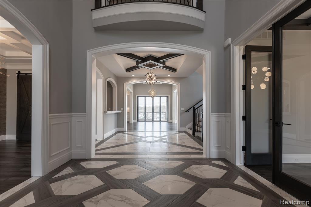 Entryway featuring dark marble finish floors, a wainscoted wall, inlaid floor details, arched walkways, and a decorative wall