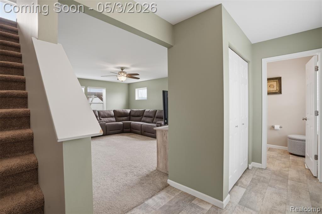 Stairway featuring ceiling fan and carpet