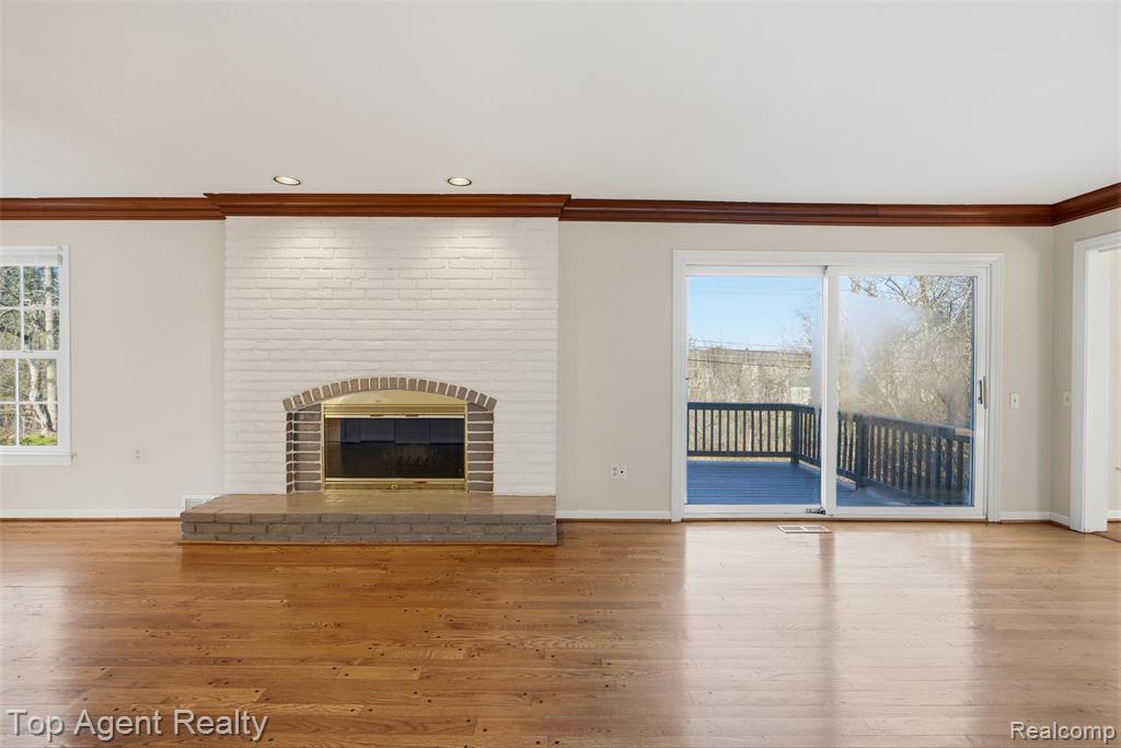 Unfurnished living room with ornamental molding, wood-type flooring, a brick fireplace, and recessed lighting
