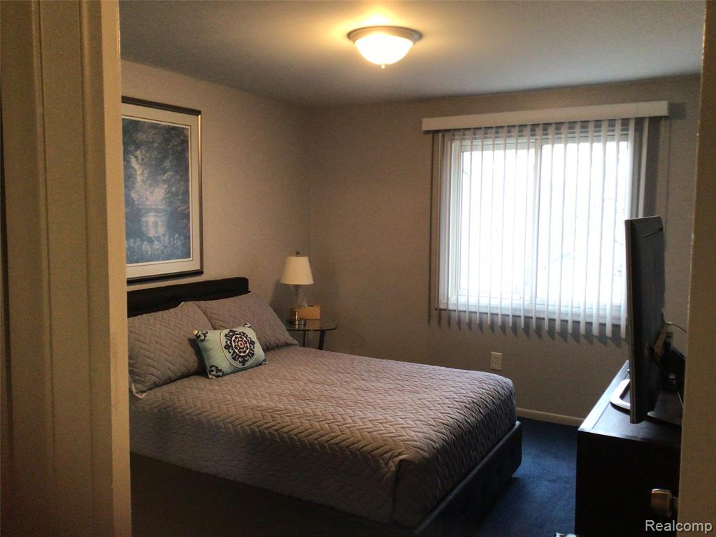 Bedroom with dark colored carpet and baseboards