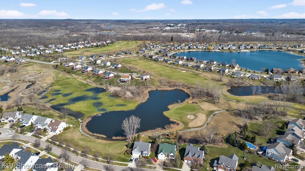 View of property location featuring nearby suburban area, a large body of water, and a golf course