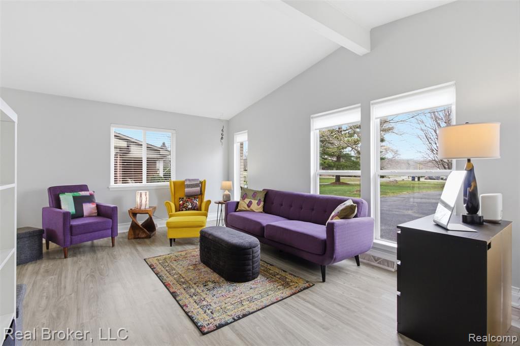 Living area featuring light wood-style floors and vaulted ceiling with beams
