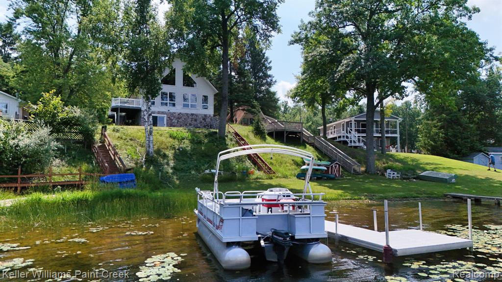 Waterfront property featuring a private dock, sloped grassy terrain, and mature trees