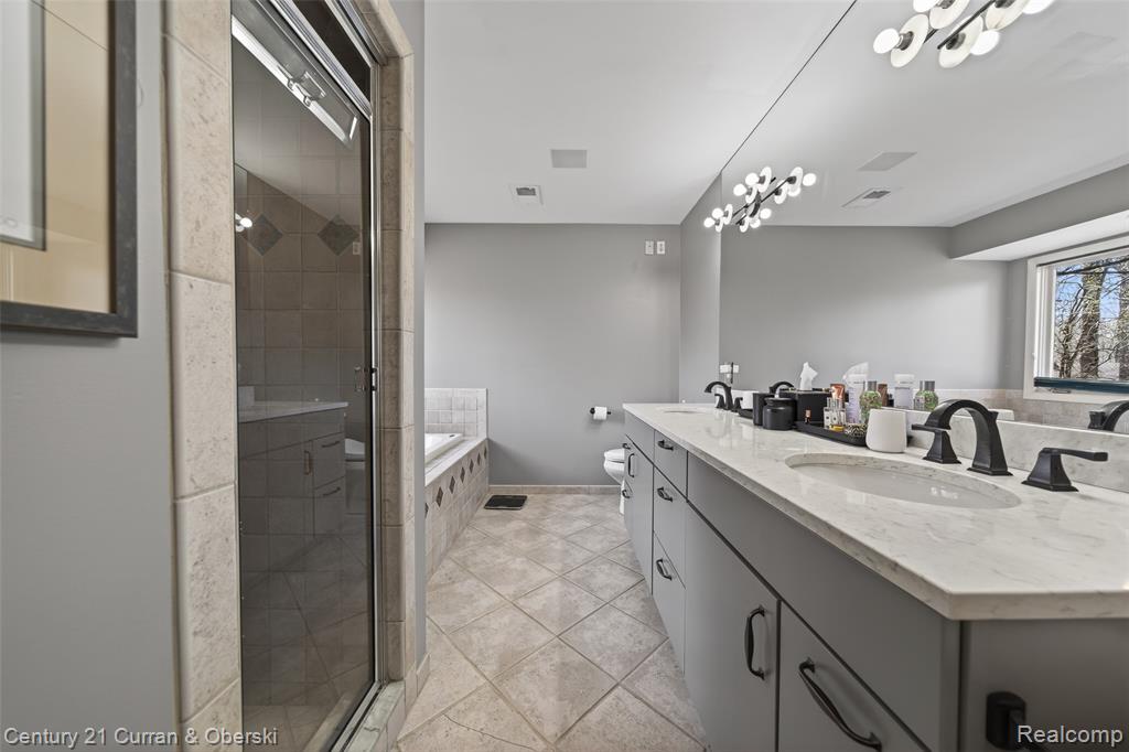 Bathroom featuring double vanity, a garden tub, light tile patterned flooring, a shower stall, and a chandelier