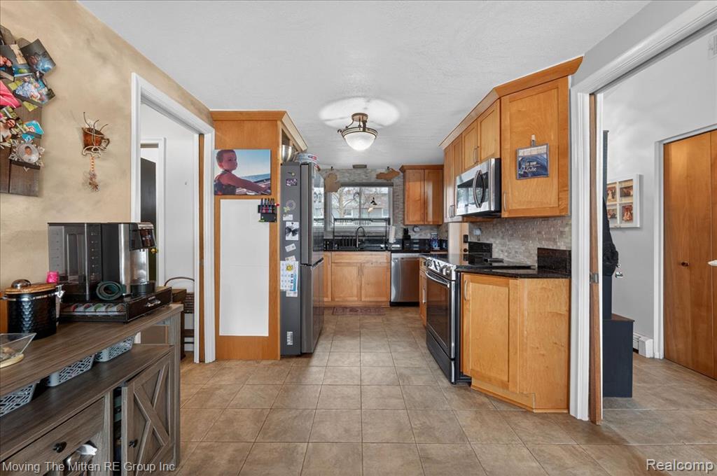 Kitchen featuring stainless steel appliances, backsplash, and wood finish cabinets