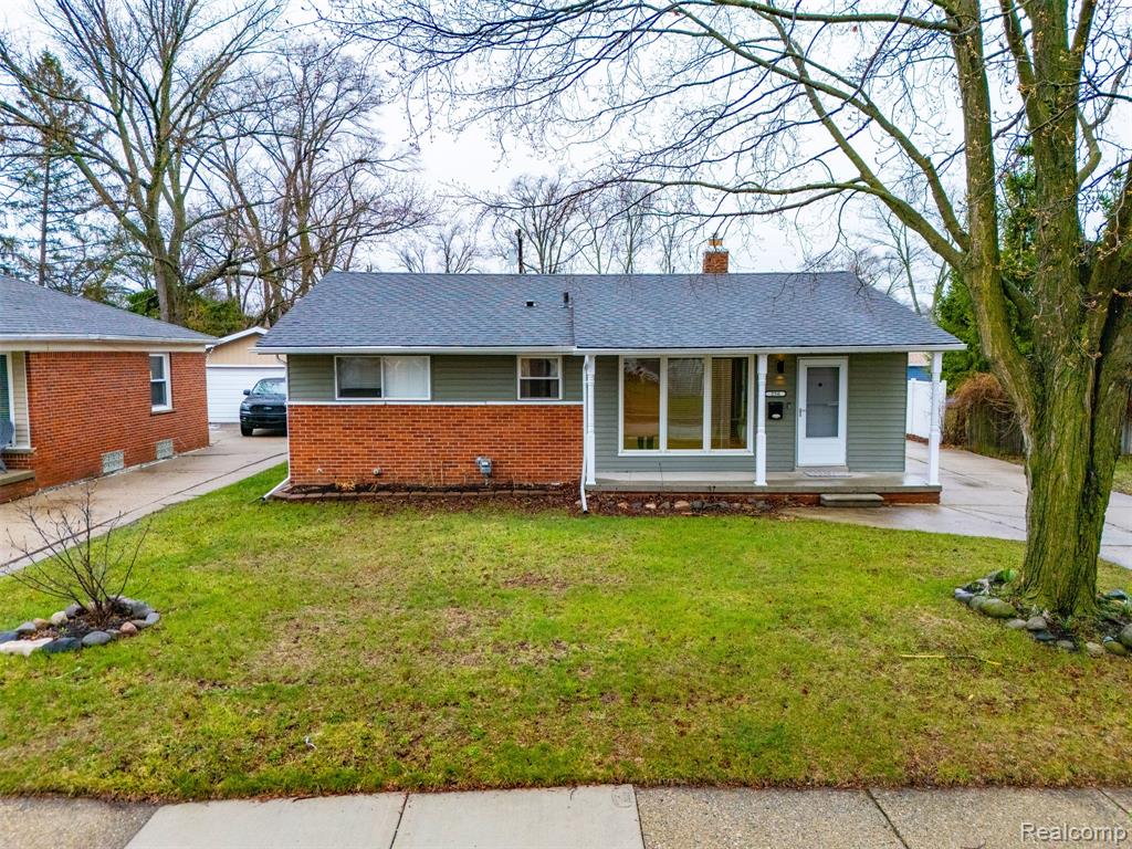 View of front of home with a chimney, a front lawn, brick siding, and a porch