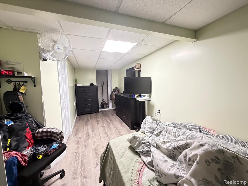 Bedroom featuring light wood-style flooring, a paneled ceiling, and a closet