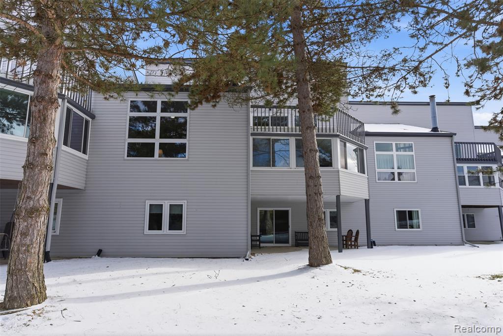 Snow covered back of property featuring a patio area and a balcony