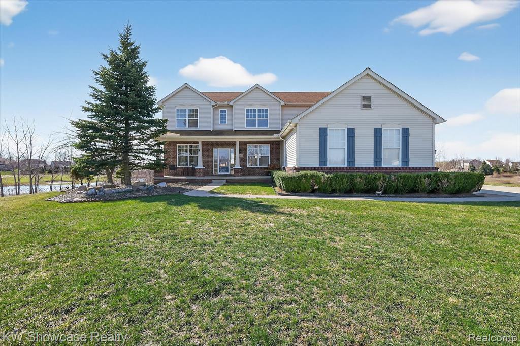 Traditional home with covered porch, a front lawn, and brick siding