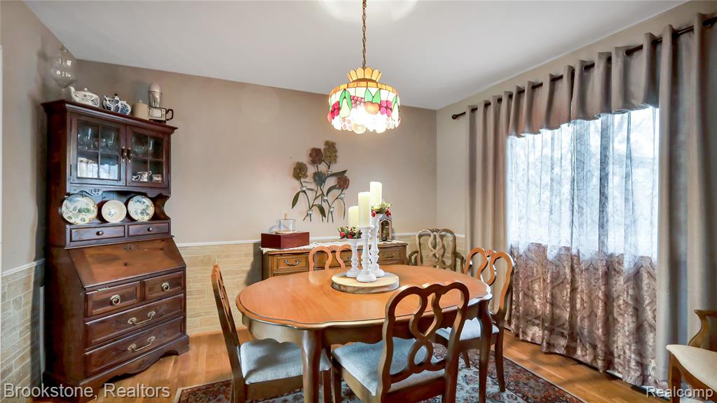 Dining space with wood finished floors and a wainscoted wall