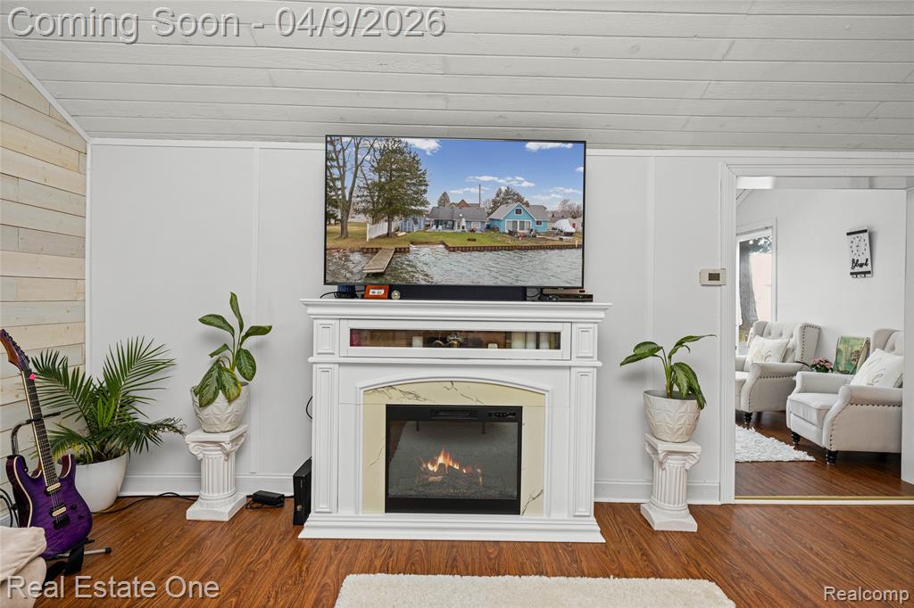 Detailed view of a glass covered fireplace, wood finished floors, wooden ceiling, and wooden walls