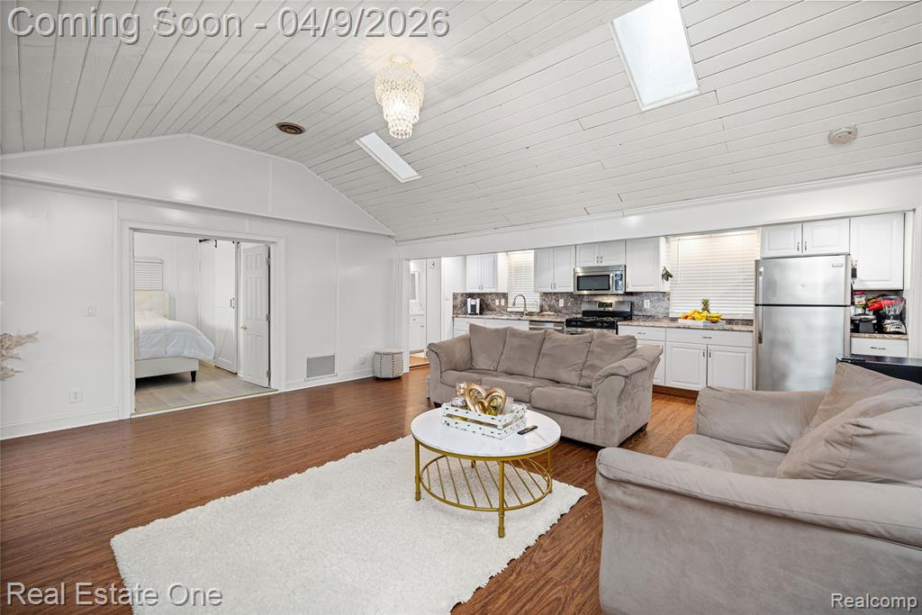 Living room with a skylight, wood finished floors, and wood ceiling