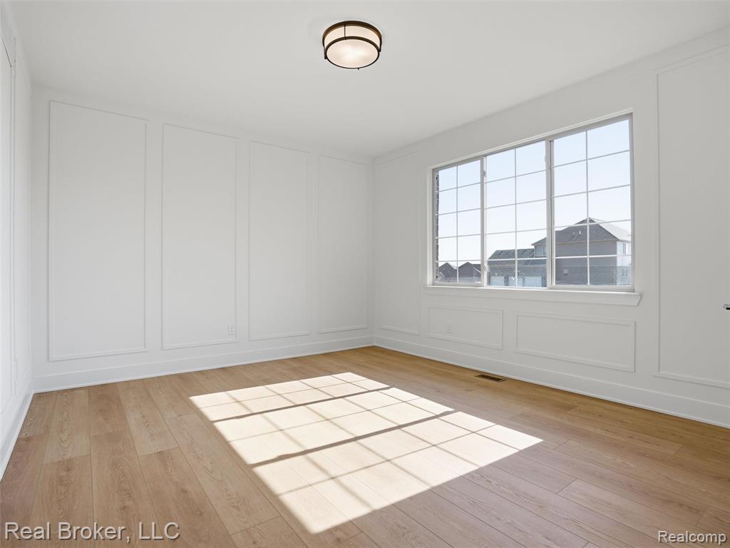 Spare room with a decorative wall and light wood-style flooring